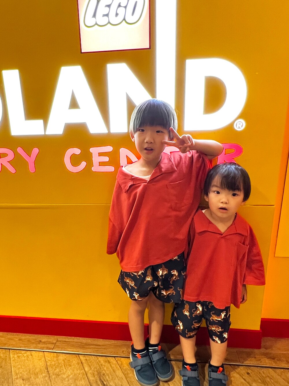 レッド系のセットアップ、ブルー系のその他パンツ、ブルー系のスニーカーを着用したキッズの夏コーディネートの2枚目の写真