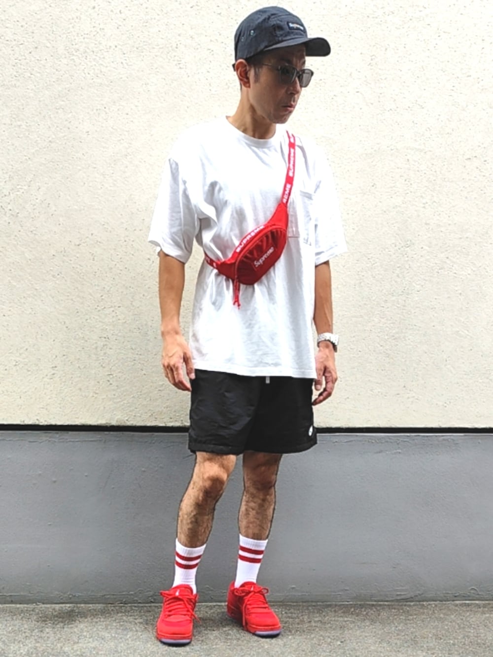 レッド系のボディバッグ/ウエストポーチ、ホワイト系のTシャツ/カットソー、ブラック系のスウェットパンツを着用したメンズの夏コーディネートの3枚目の写真