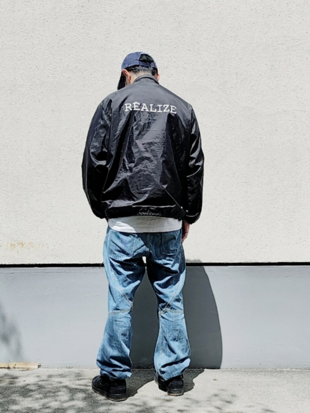 ブラック系のナイロンジャケット、ホワイト系のTシャツ/カットソー、ブルー系のデニムパンツを着用したメンズの夏コーディネートの3枚目の写真