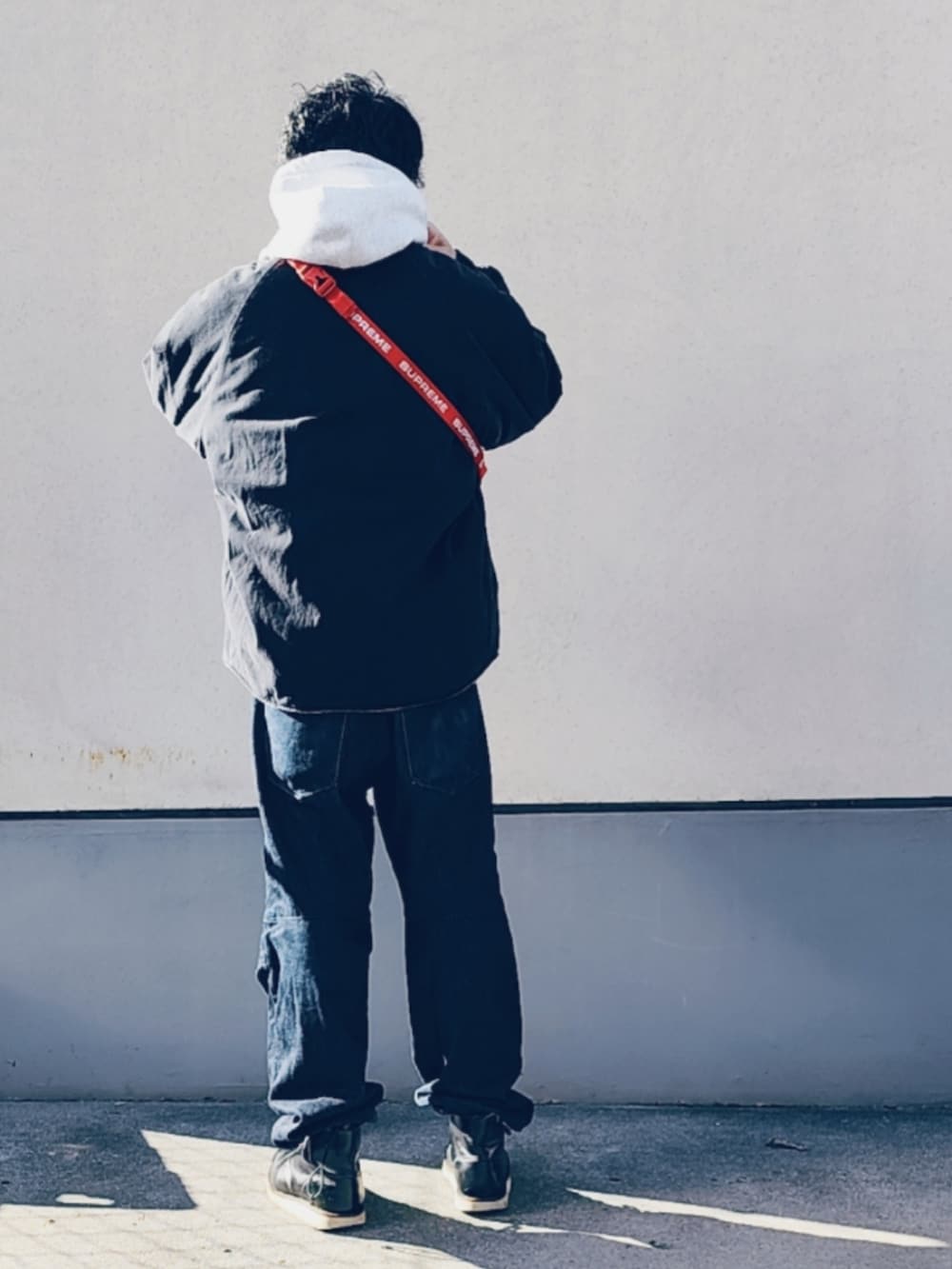 レッド系のボディバッグ/ウエストポーチ、グレー系のパーカー、ブラック系のブルゾンを着用したメンズの冬コーディネートの3枚目の写真