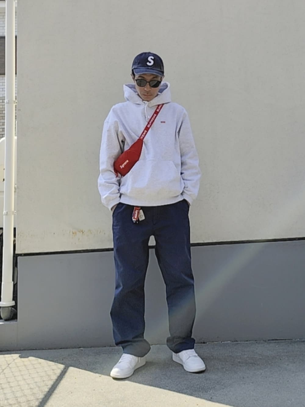 レッド系のボディバッグ/ウエストポーチ、グレー系のパーカー、ホワイト系のスニーカーを着用したメンズの春コーディネートの2枚目の写真