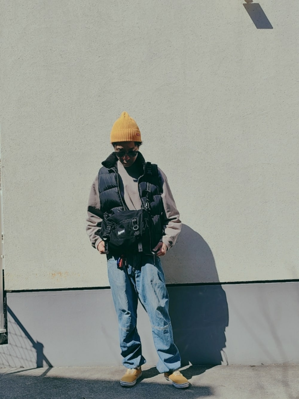 ブラック系のダウンベスト、グレー系のスウェット、ブラック系のボディバッグ/ウエストポーチを着用したメンズの春コーディネートの4枚目の写真