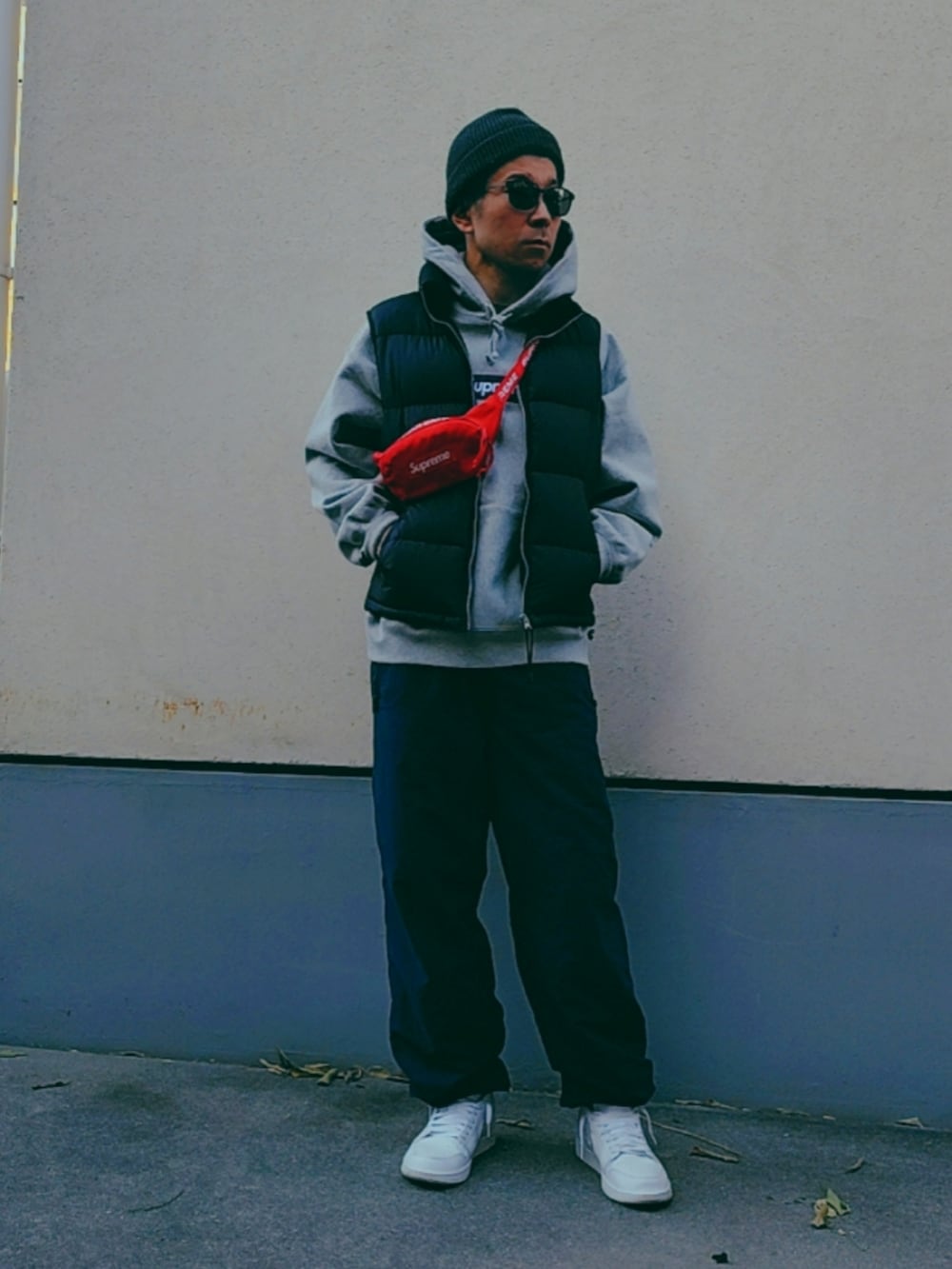 レッド系のボディバッグ/ウエストポーチ、グレー系のパーカー、ブラック系のダウンベストを着用したメンズの冬コーディネートの2枚目の写真