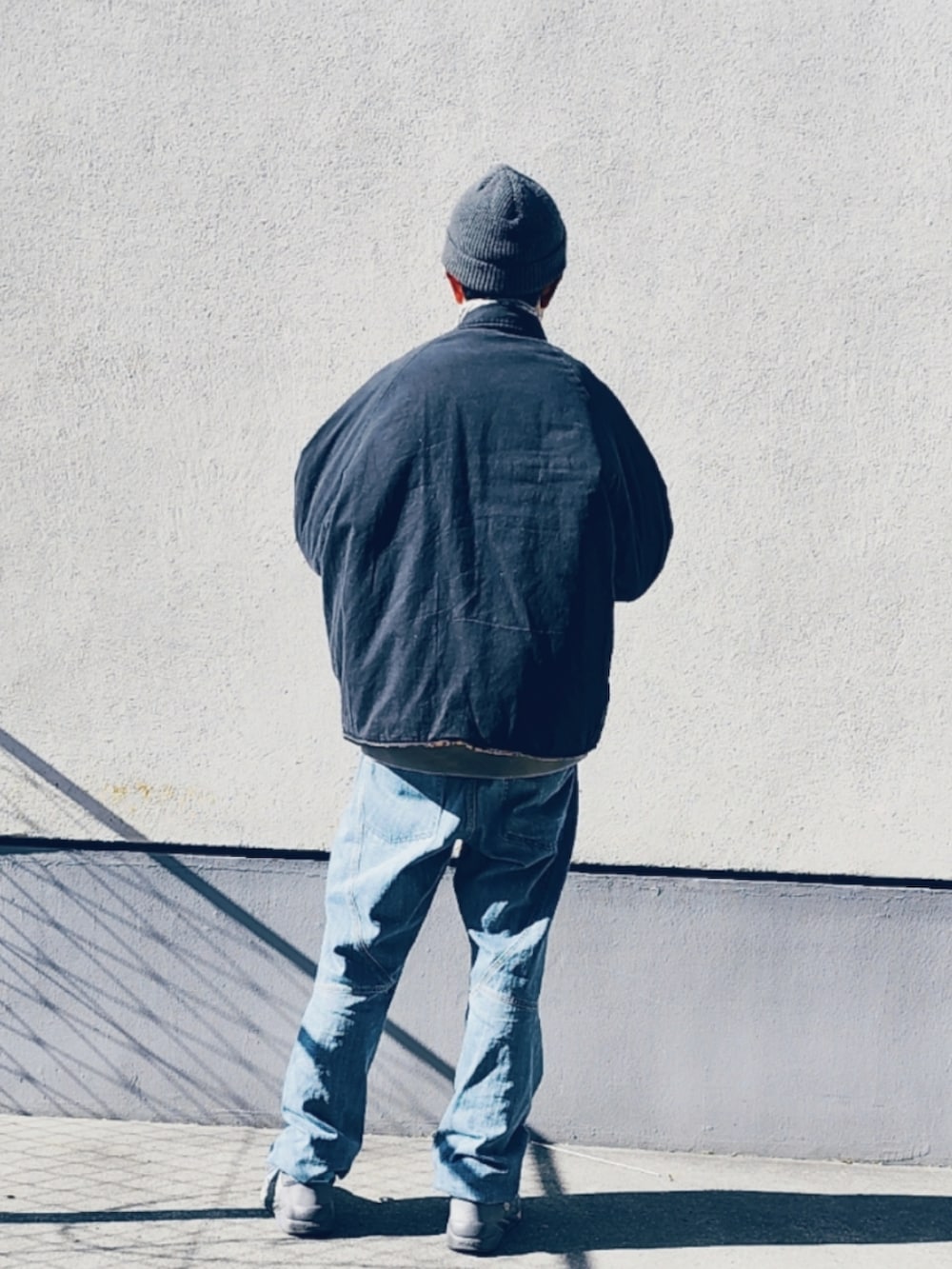 ブラック系のブルゾン、ブルー系のデニムパンツ、パープル系のスニーカーを着用したメンズの冬コーディネートの2枚目の写真