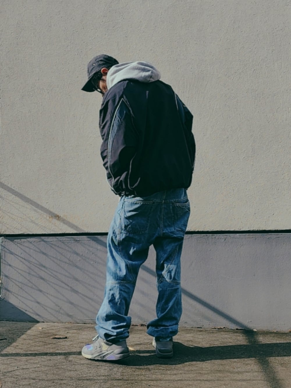 グレー系のパーカー、ブラック系のナイロンジャケット、パープル系のスニーカーを着用したメンズの冬コーディネートの2枚目の写真