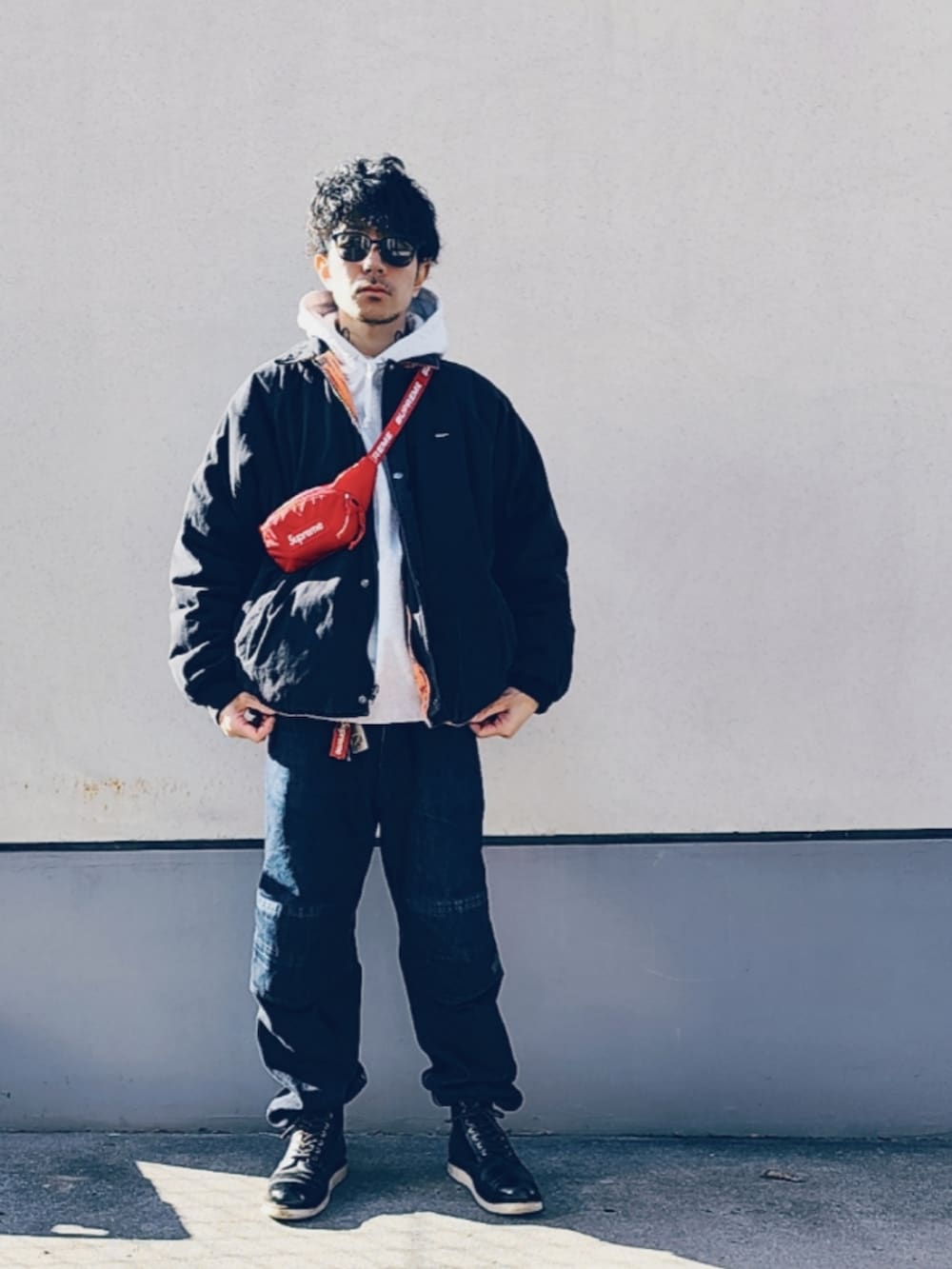 レッド系のボディバッグ/ウエストポーチ、グレー系のパーカー、ブラック系のブルゾンを着用したメンズの冬コーディネートの2枚目の写真