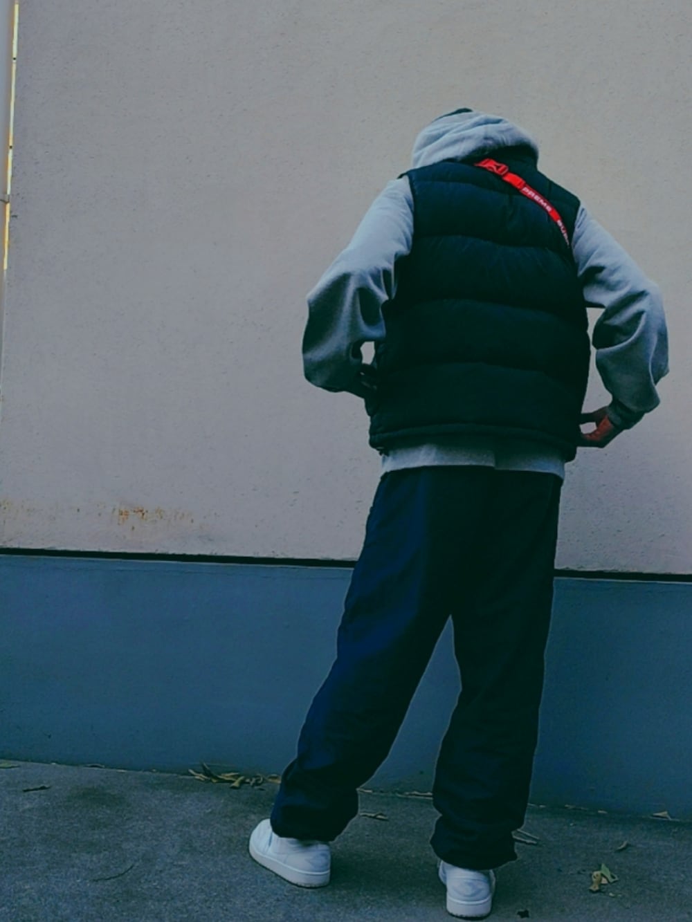 レッド系のボディバッグ/ウエストポーチ、グレー系のパーカー、ブラック系のダウンベストを着用したメンズの冬コーディネートの3枚目の写真