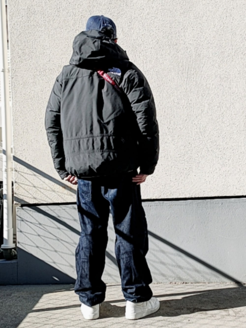 グレー系のスウェット、レッド系のボディバッグ/ウエストポーチ、ブラック系のダウンジャケット/コートを着用したメンズの冬コーディネートの2枚目の写真