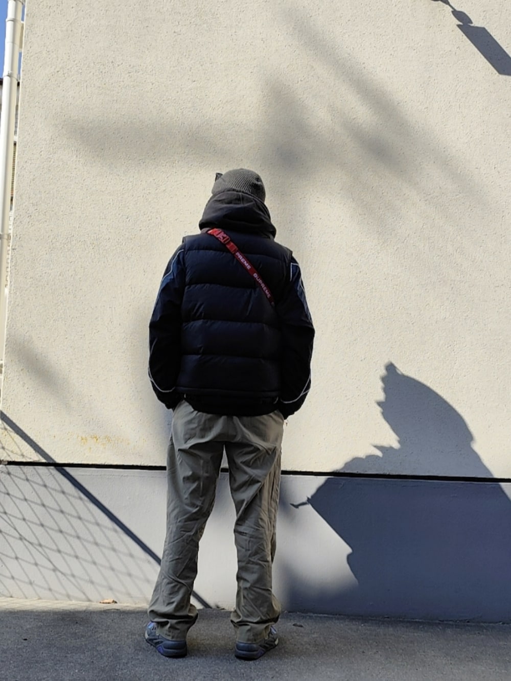 レッド系のボディバッグ/ウエストポーチ、ブラック系のダウンベスト、ブラック系のナイロンジャケットを着用したメンズの冬コーディネートの2枚目の写真