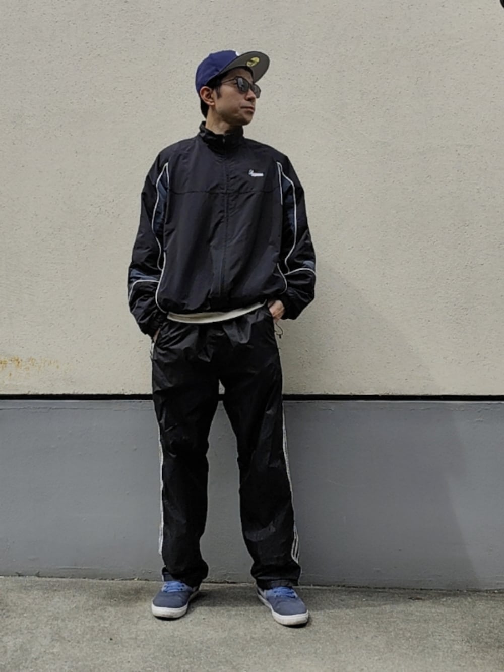 ブルー系のスニーカー、ブラック系のその他パンツ、ブラック系のナイロンジャケットを着用したメンズの春コーディネートの2枚目の写真