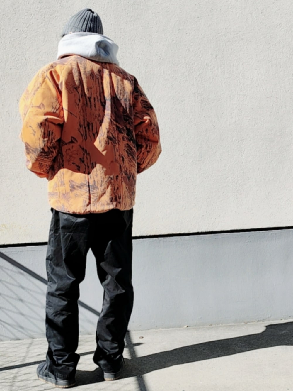 グレー系のパーカー、オレンジ系のブルゾン、ブラック系のチノパンツを着用したメンズの冬コーディネートの3枚目の写真