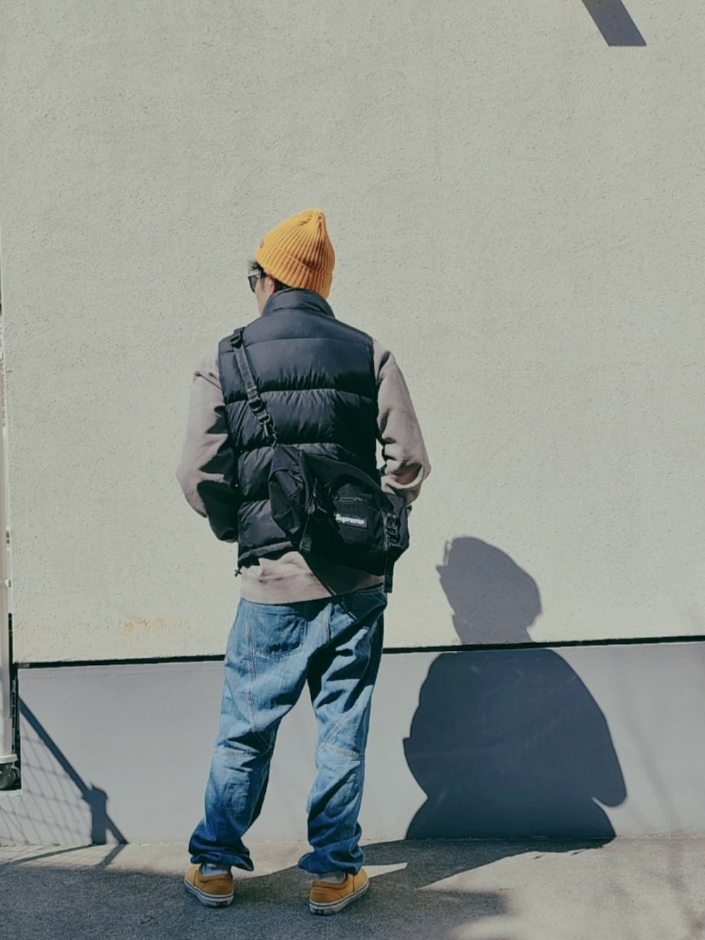 ブラック系のダウンベスト、グレー系のスウェット、ブラック系のボディバッグ/ウエストポーチを着用したメンズの春コーディネートの3枚目の写真