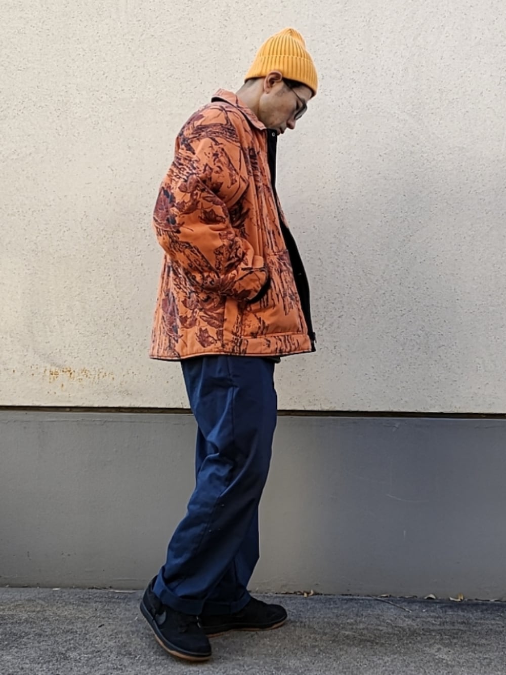 オレンジ系のブルゾン、ブラック系のスウェット、ブルー系のチノパンツを着用したメンズの冬コーディネートの3枚目の写真