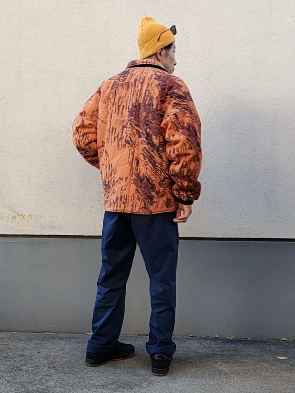 オレンジ系のブルゾン、ブラック系のスウェット、ブルー系のチノパンツを着用したメンズの冬コーディネートの2枚目の写真