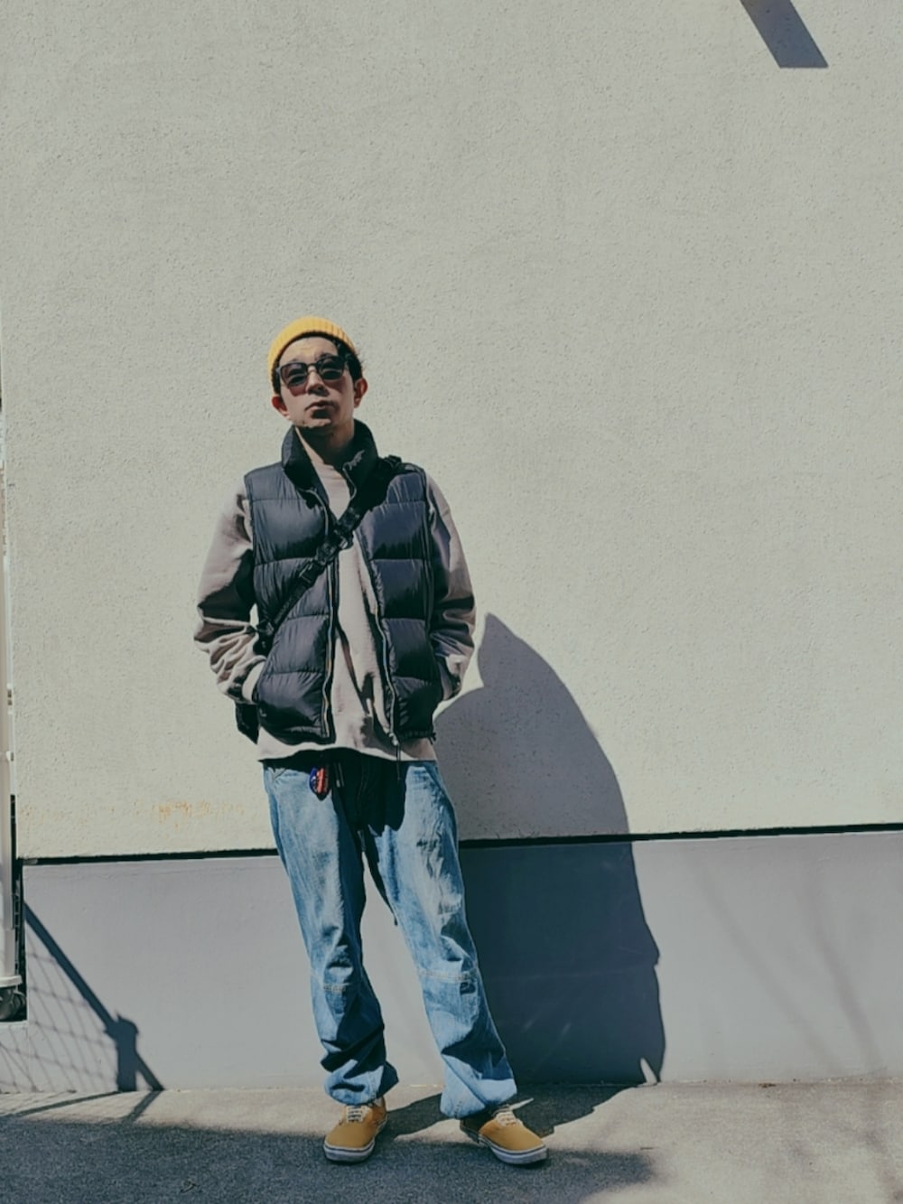 ブラック系のダウンベスト、グレー系のスウェット、ブラック系のボディバッグ/ウエストポーチを着用したメンズの春コーディネートの2枚目の写真