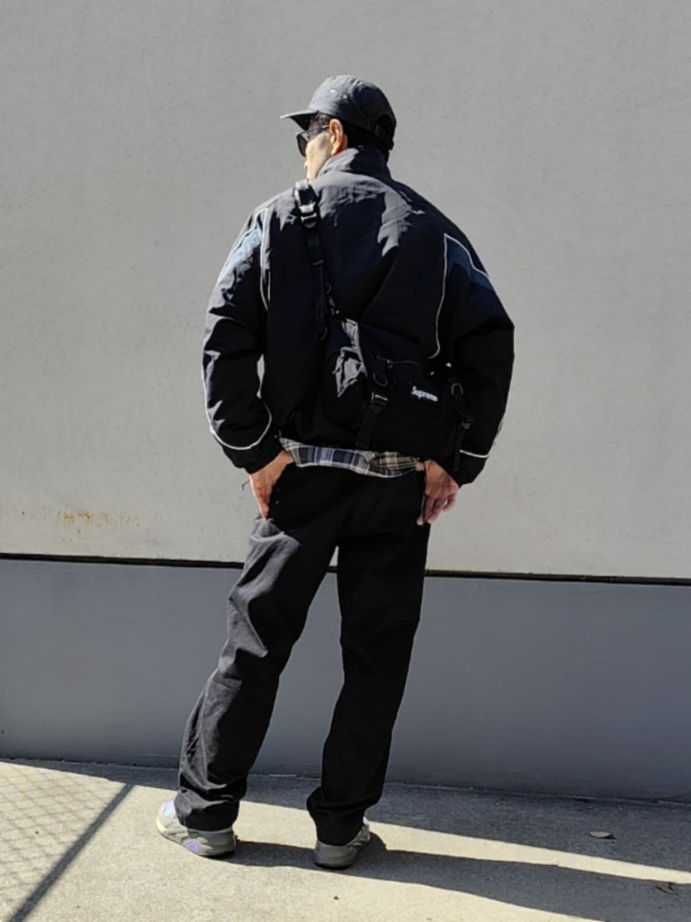 ブラック系のナイロンジャケット、グレー系のシャツ/ブラウス、ブラック系のボディバッグ/ウエストポーチを着用したメンズの春コーディネートの3枚目の写真