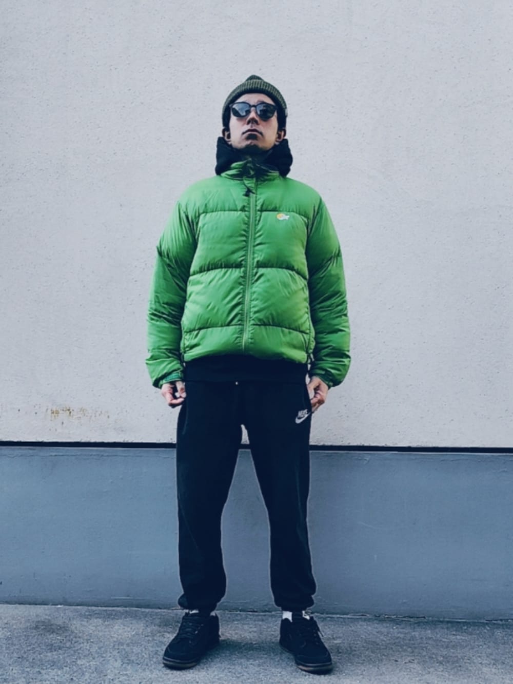 グリーン系のダウンジャケット/コート、ブラック系のパーカー、ブラック系のスウェットパンツを着用したメンズの冬コーディネートの2枚目の写真