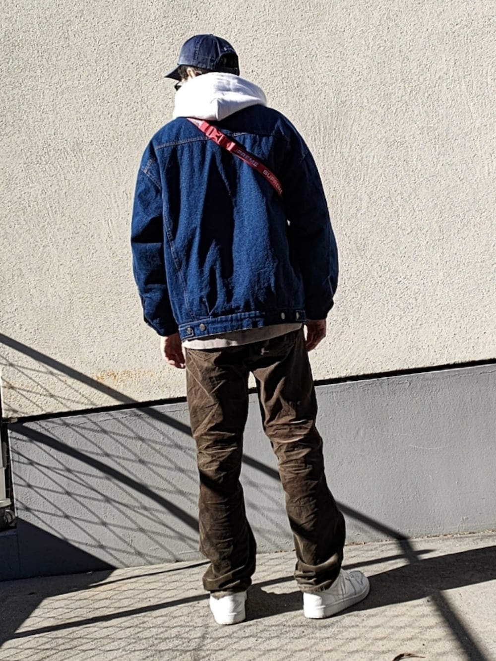 レッド系のボディバッグ/ウエストポーチ、グレー系のスウェット、ブルー系のデニムジャケットを着用したメンズの冬コーディネートの3枚目の写真