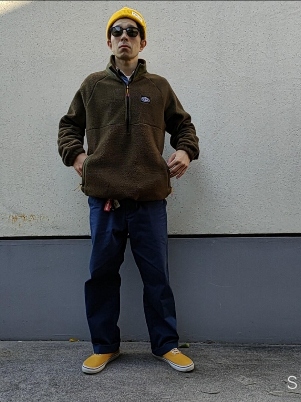 グリーン系のブルゾン、ブルー系のチノパンツ、イエロー系のスニーカーを着用したメンズの秋コーディネートの2枚目の写真