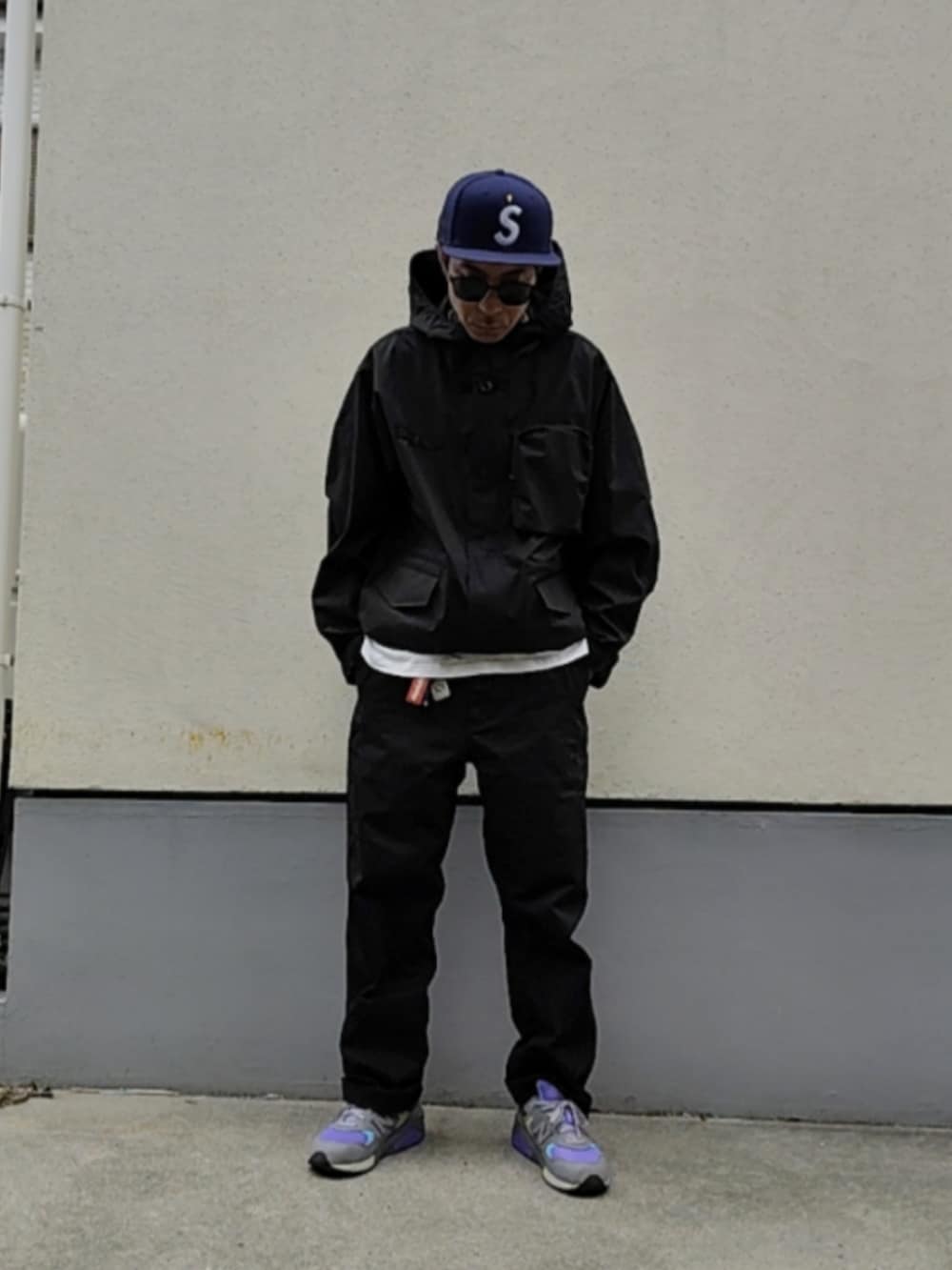 ブラック系のチノパンツ、パープル系のスニーカー、ブラック系のナイロンジャケットを着用したメンズの春コーディネートの2枚目の写真