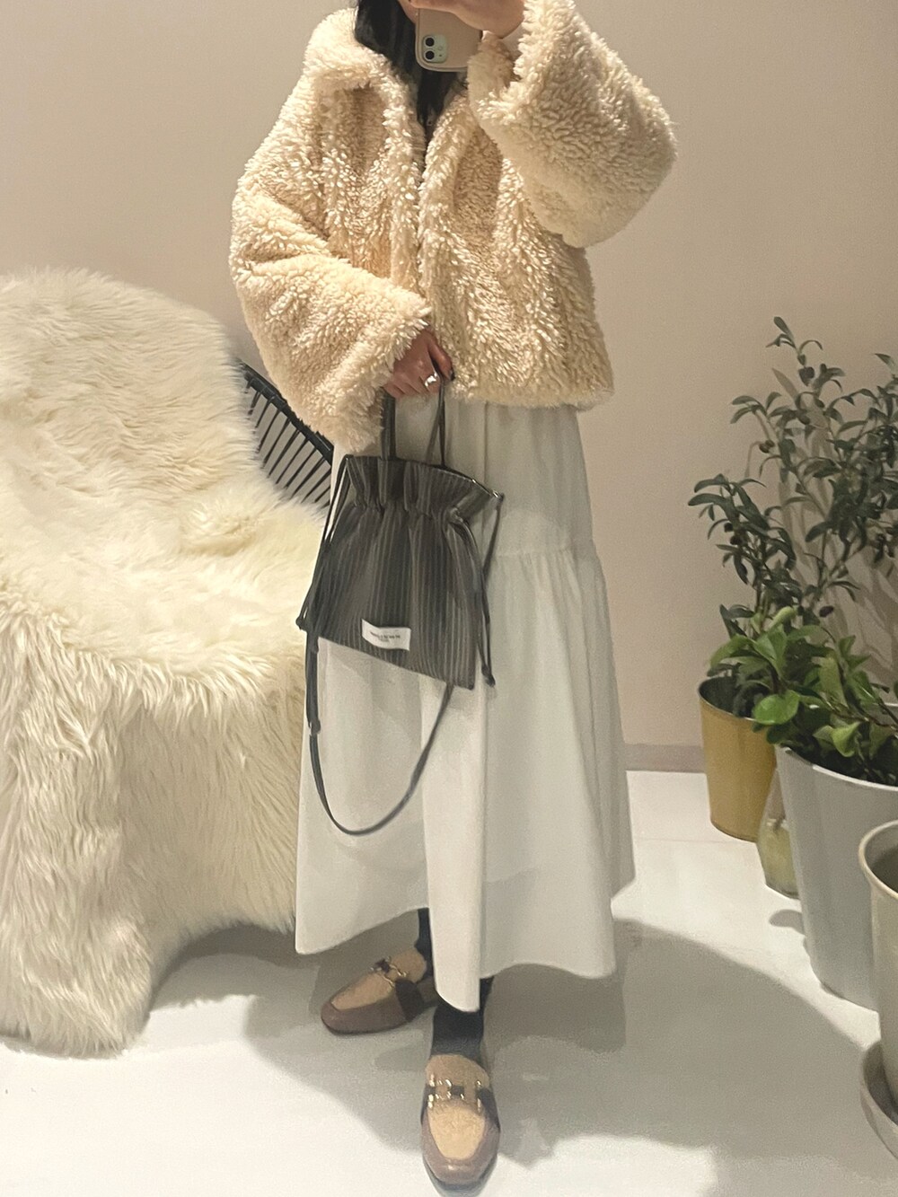 グレー系のショルダーバッグ、ホワイト系のスカート、ホワイト系のスカートを着用したレディースの冬コーディネートの2枚目の写真