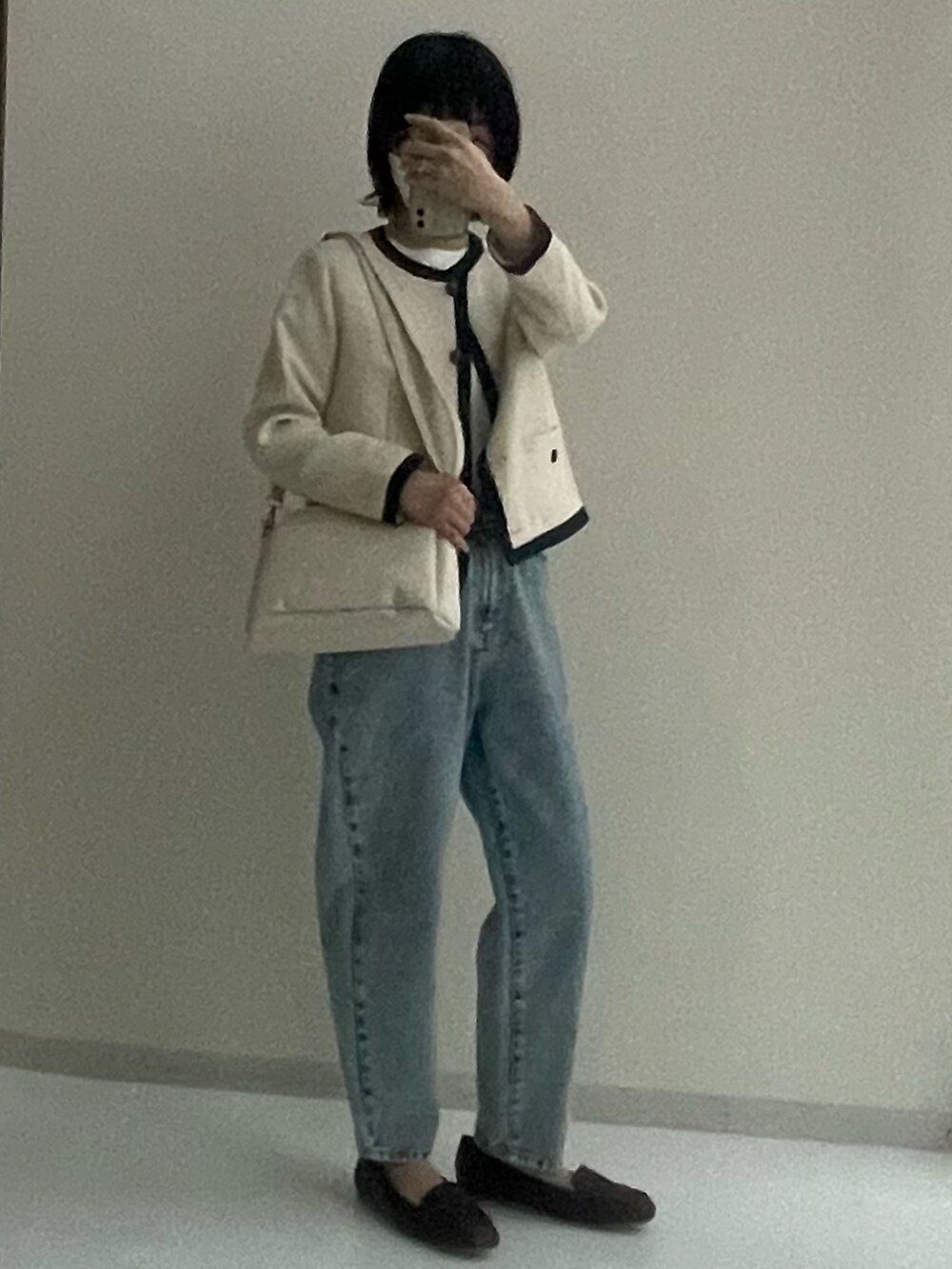 ホワイト系のノーカラージャケット、ブルー系のデニムパンツ、ホワイト系のショルダーバッグを着用したレディースの夏コーディネートの2枚目の写真