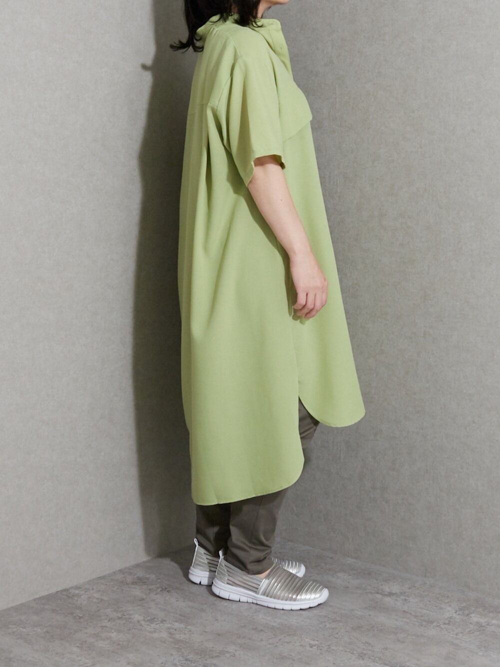 グリーン系のワンピース、ブラウン系のチノパンツ、シルバー系のスニーカーを着用したレディースの夏コーディネートの2枚目の写真