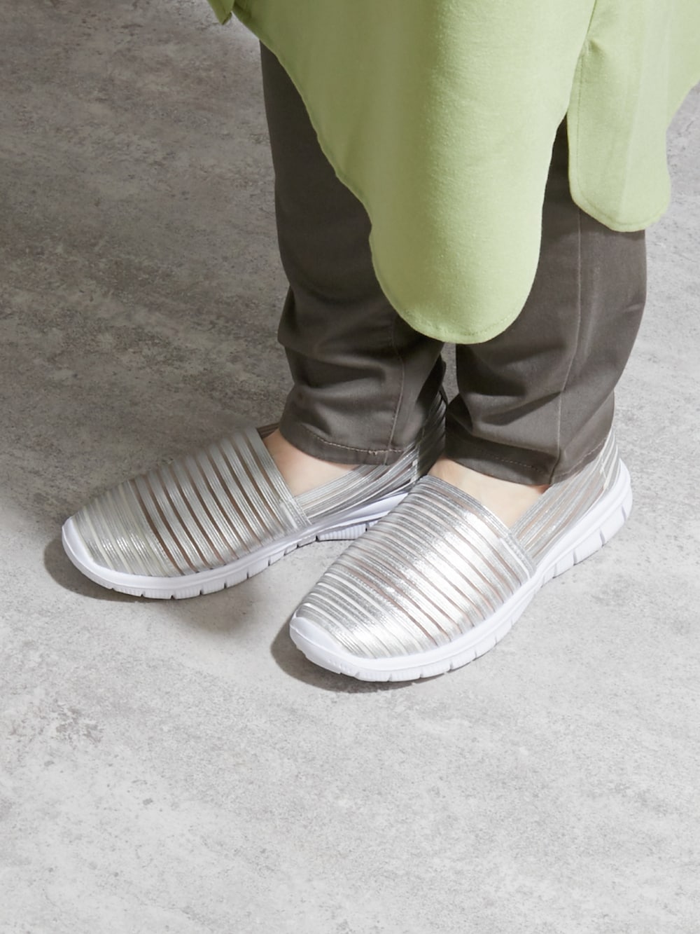 グリーン系のワンピース、ブラウン系のチノパンツ、シルバー系のスニーカーを着用したレディースの夏コーディネートの3枚目の写真