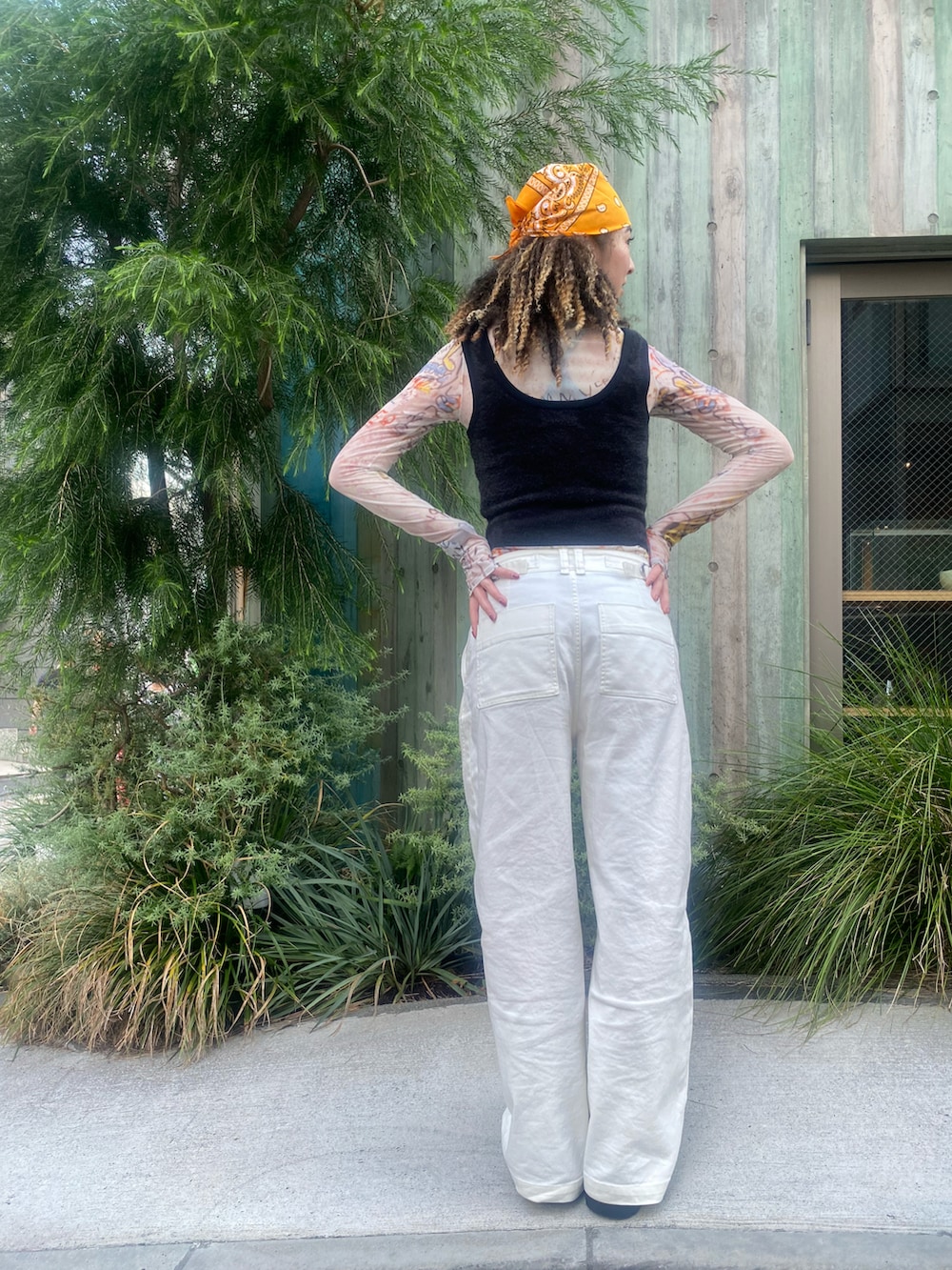 ブラック系のタンクトップ、オレンジ系のその他トップス、ホワイト系のパンツを着用したレディースの秋コーディネートの3枚目の写真