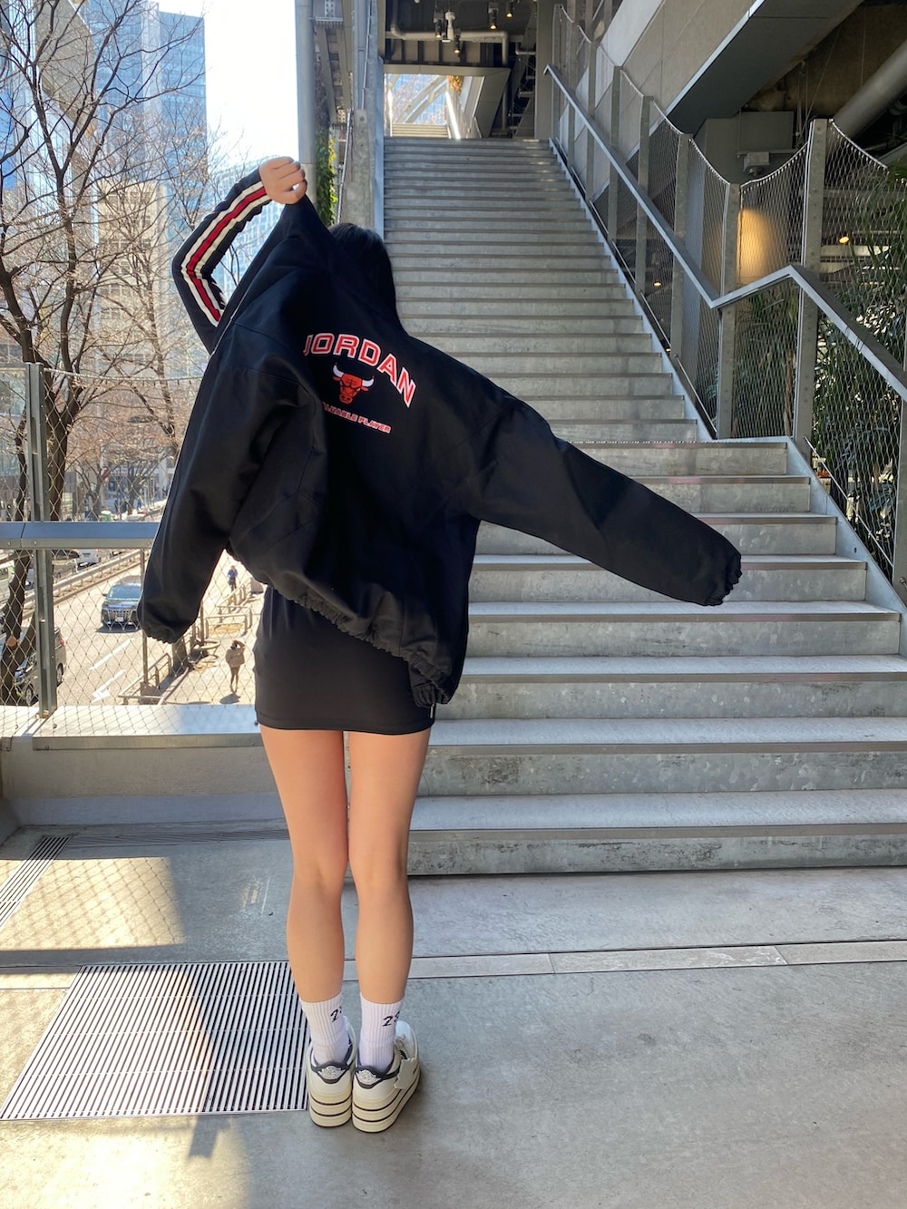 ブラック系のワンピース、ブラック系のジャケット/アウター、ホワイト系のスニーカーを着用したレディースの冬コーディネートの2枚目の写真