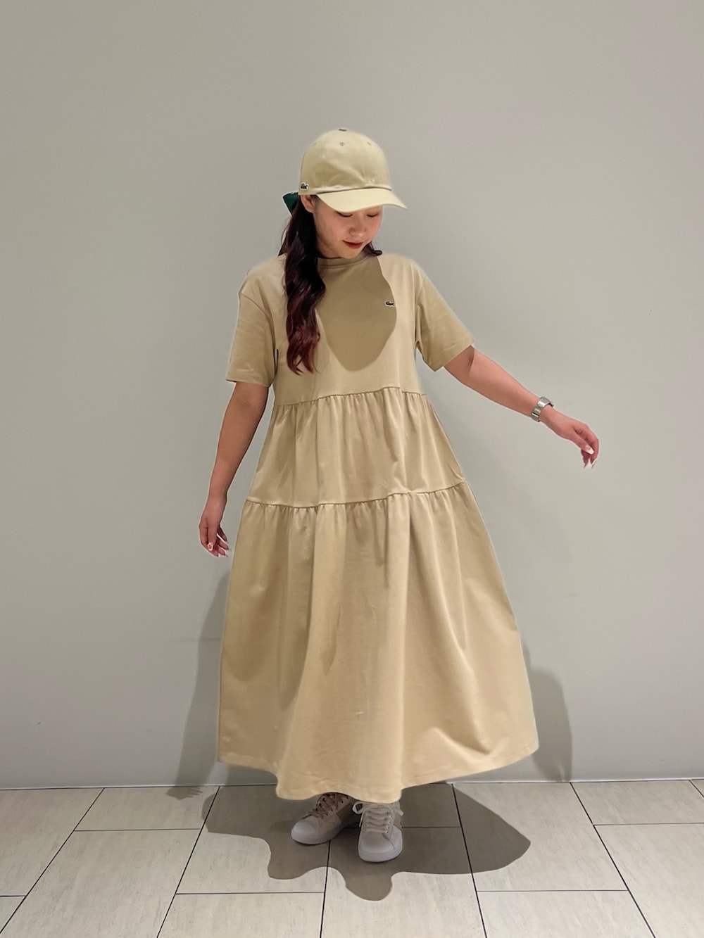 ホワイト系のスニーカー、ベージュ系のワンピース、ブルー系のトートバッグを着用したレディースの夏コーディネートの3枚目の写真