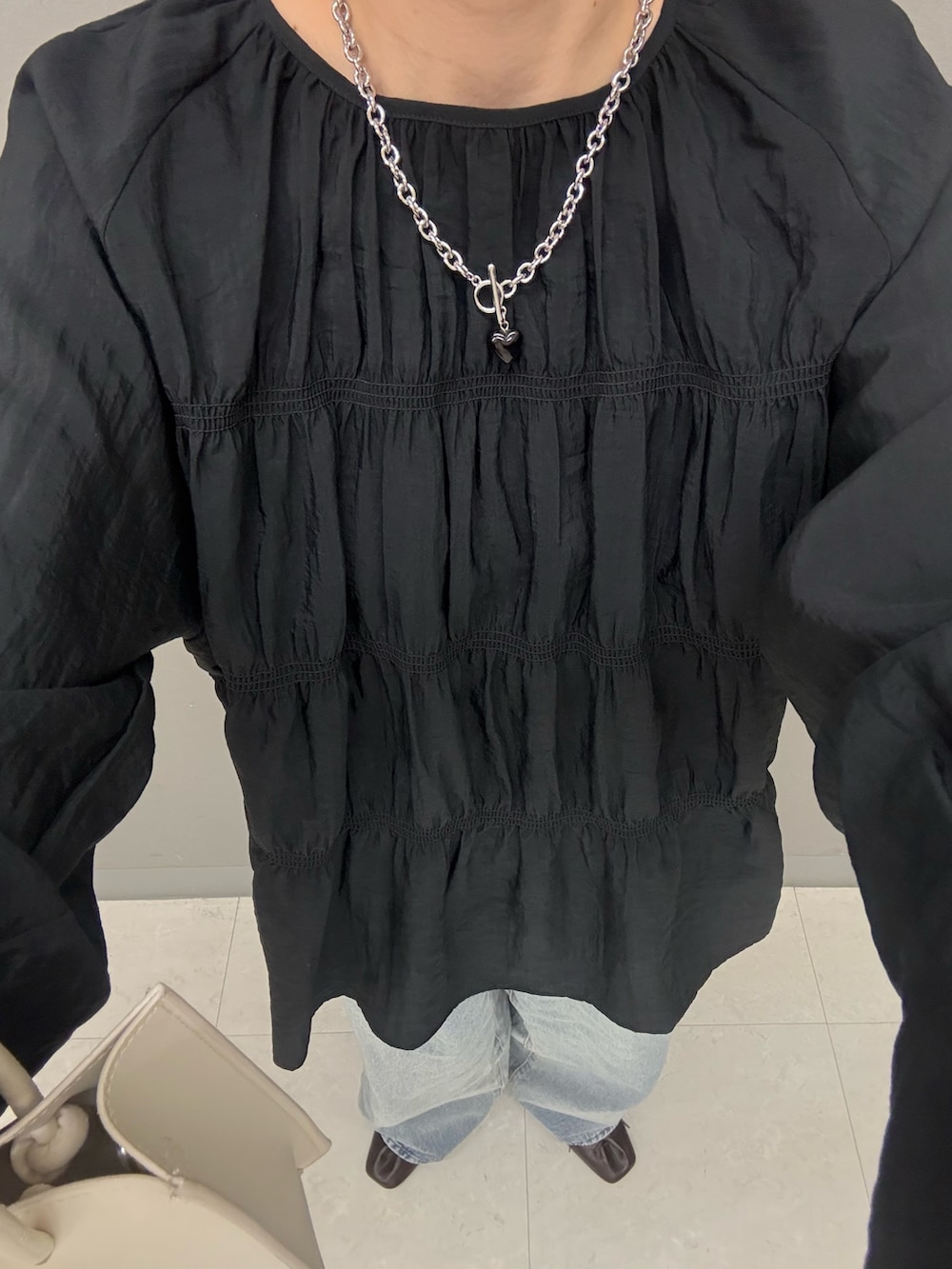 ブラック系のデニムパンツ、ホワイト系のハンドバッグ、ブラック系のシャツ/ブラウスを着用したレディースの春コーディネートの5枚目の写真