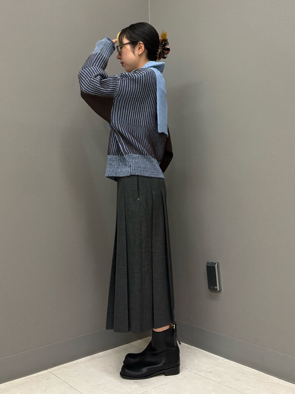 グレー系のスカート、ブルー系のニット/セーター、ブラック系のブーツを着用したレディースの秋コーディネートの3枚目の写真