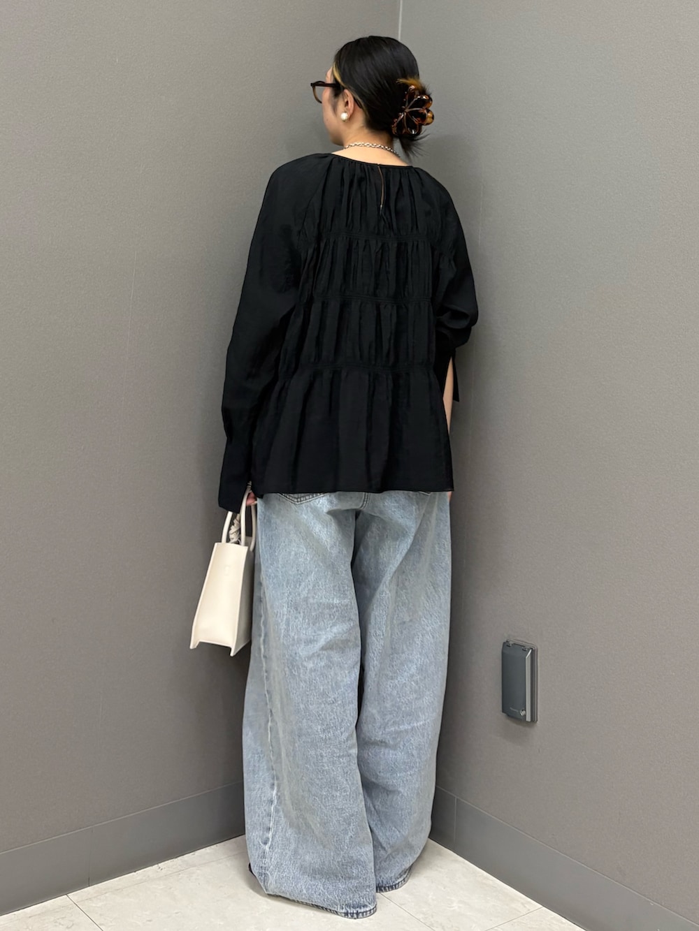 ブラック系のデニムパンツ、ホワイト系のハンドバッグ、ブラック系のシャツ/ブラウスを着用したレディースの春コーディネートの4枚目の写真