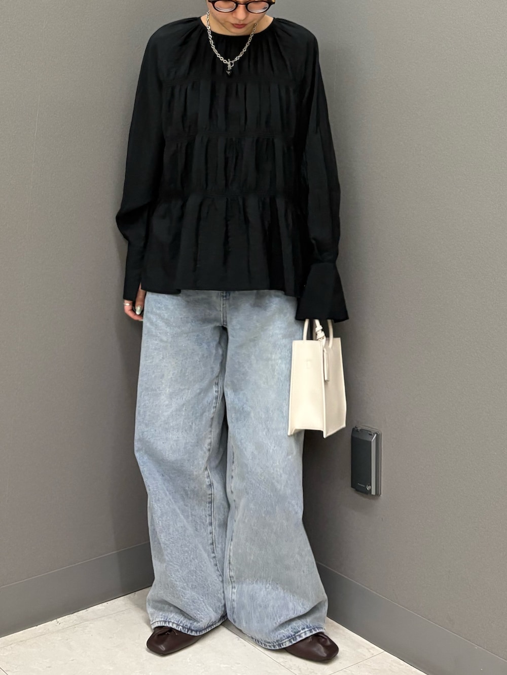 ブラック系のデニムパンツ、ホワイト系のハンドバッグ、ブラック系のシャツ/ブラウスを着用したレディースの春コーディネートの2枚目の写真