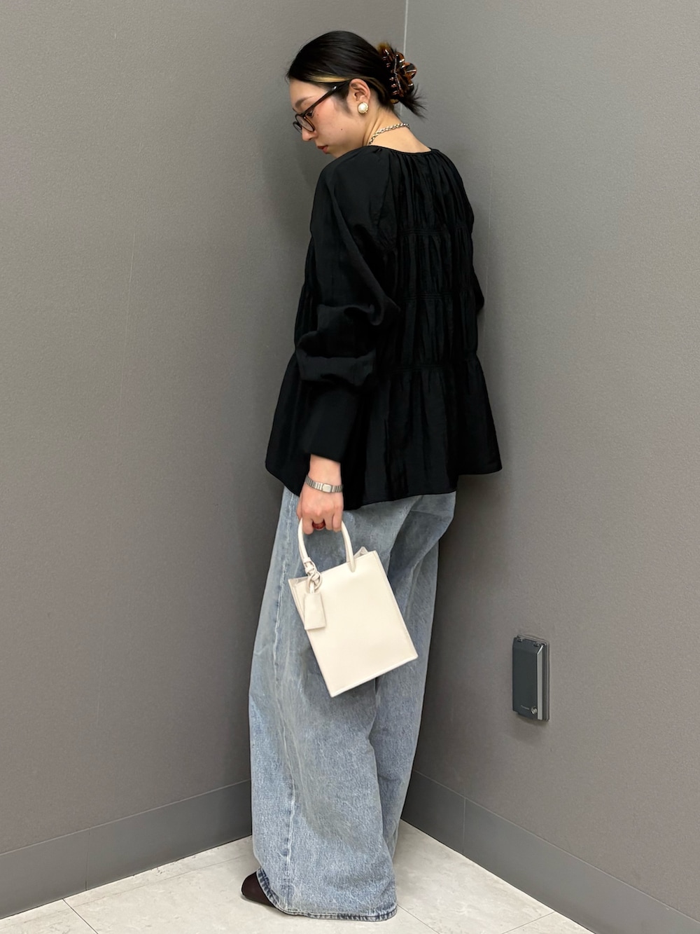 ブラック系のデニムパンツ、ホワイト系のハンドバッグ、ブラック系のシャツ/ブラウスを着用したレディースの春コーディネートの3枚目の写真