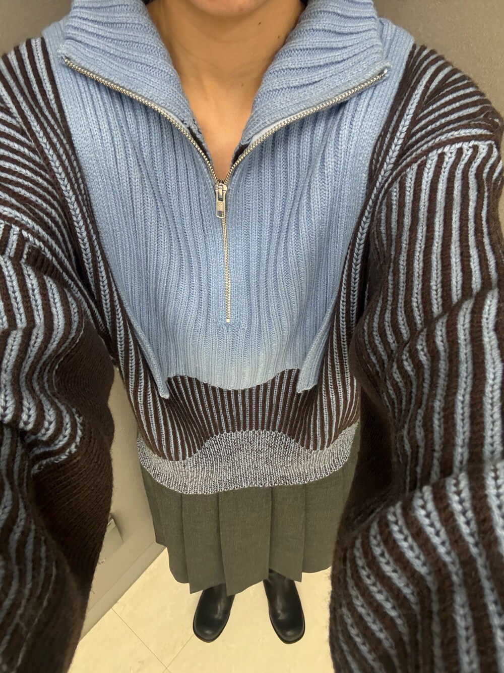 グレー系のスカート、ブルー系のニット/セーター、ブラック系のブーツを着用したレディースの秋コーディネートの4枚目の写真