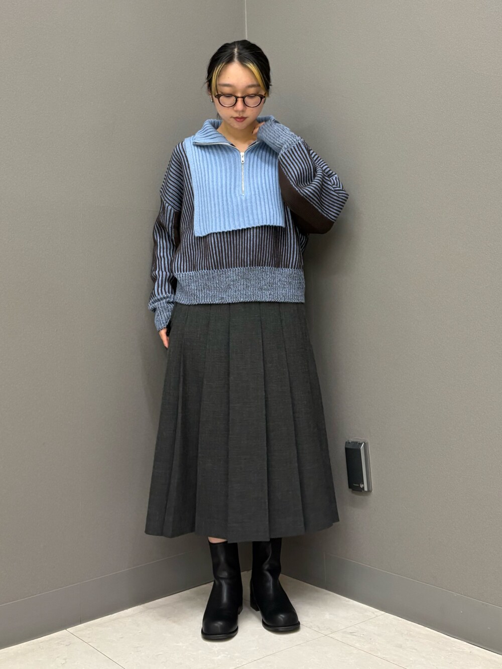 グレー系のスカート、ブルー系のニット/セーター、ブラック系のブーツを着用したレディースの秋コーディネートの2枚目の写真