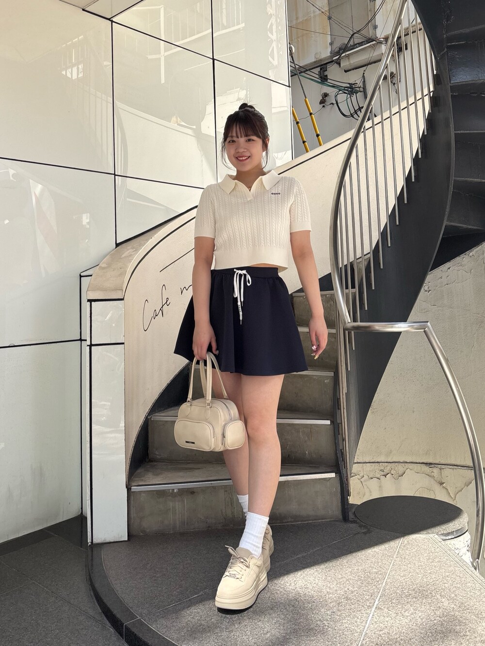 ブルー系のスカート、ホワイト系のニット/セーター、ホワイト系のボストンバッグを着用したレディースの春コーディネートの3枚目の写真