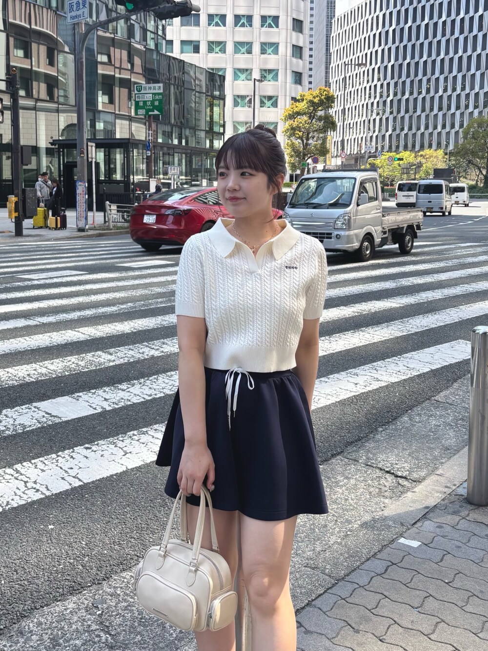 ブルー系のスカート、ホワイト系のニット/セーター、ホワイト系のボストンバッグを着用したレディースの春コーディネートの4枚目の写真