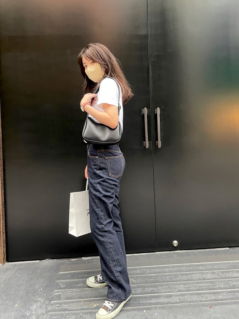 ブルー系のデニムパンツ、ブラック系のスニーカー、ブラウン系のアナログ腕時計を着用したレディースの夏コーディネートの3枚目の写真