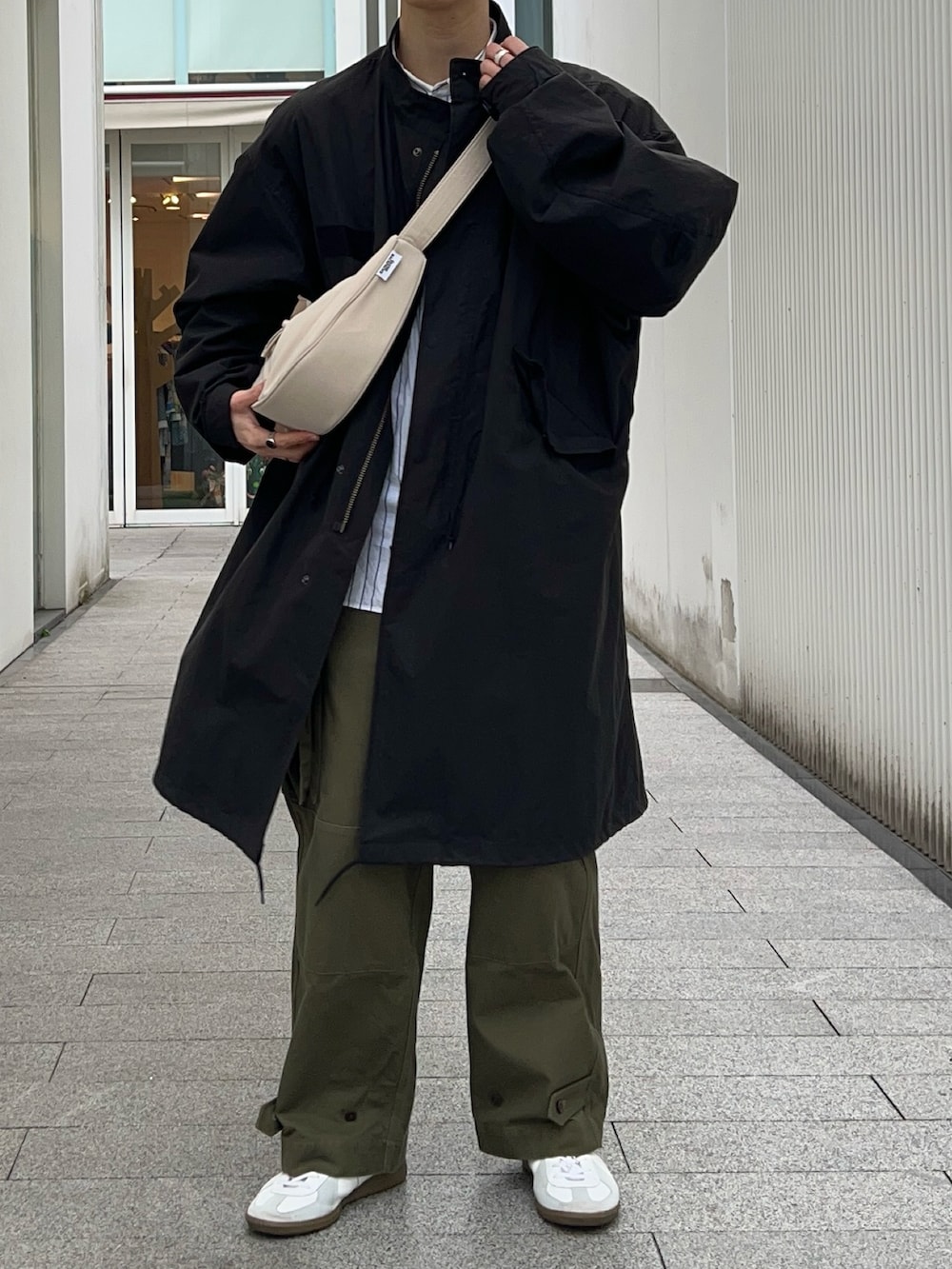 ブラック系のモッズコート、ホワイト系のシャツ/ブラウス、グリーン系のカーゴパンツを着用したメンズの春コーディネートの2枚目の写真