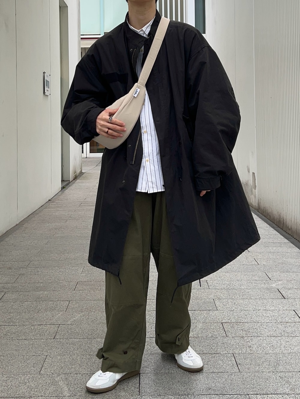 ブラック系のモッズコート、ホワイト系のシャツ/ブラウス、グリーン系のカーゴパンツを着用したメンズの春コーディネートの3枚目の写真