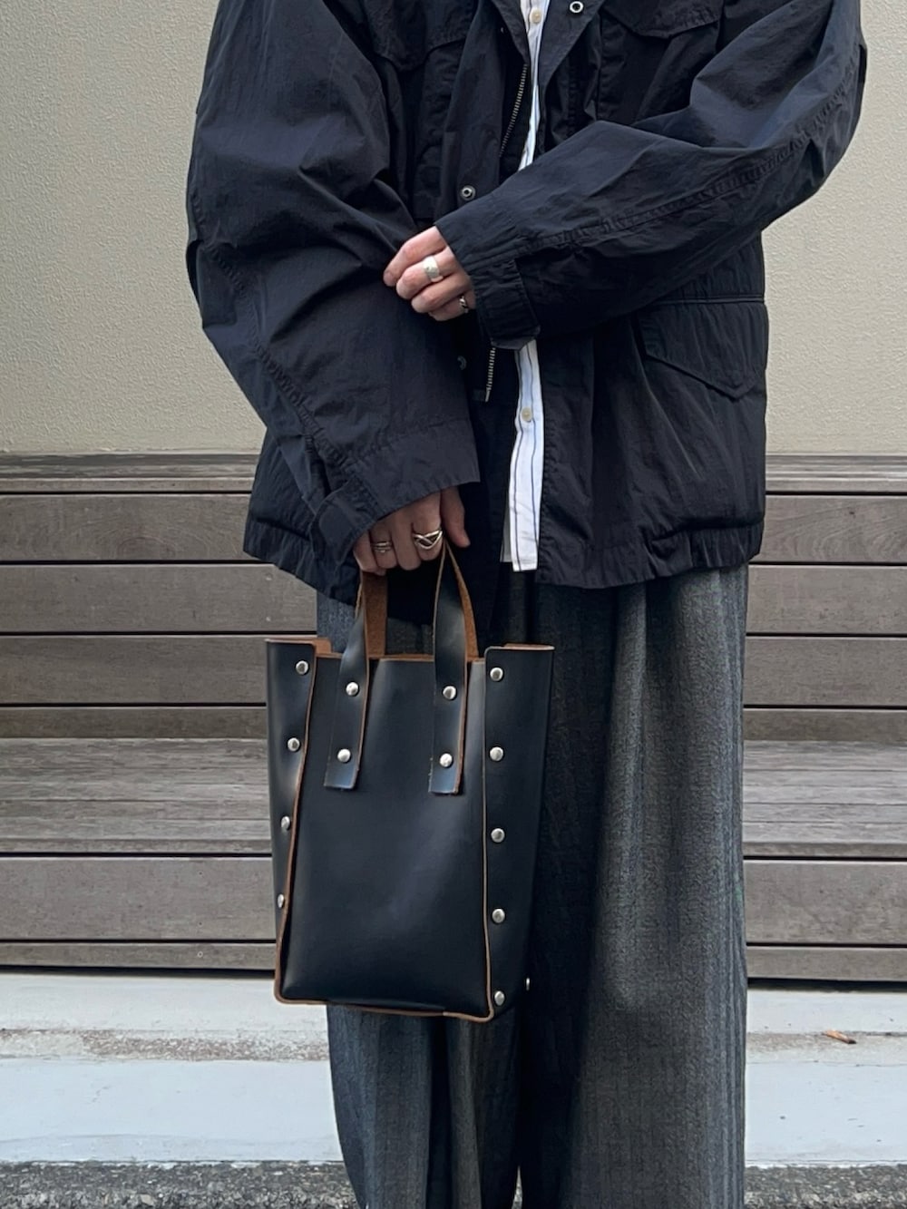 ブラック系のハンドバッグ、ホワイト系のスニーカー、ホワイト系のシャツ/ブラウスを着用したメンズの秋コーディネートの3枚目の写真