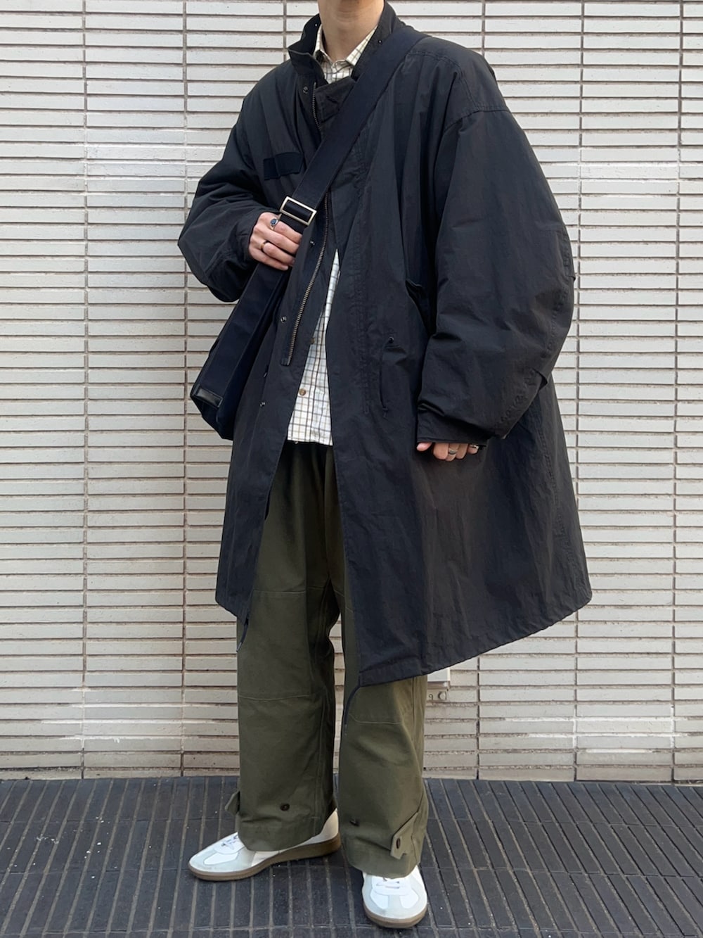 ホワイト系のスニーカー、ブラック系のショルダーバッグ、ブラック系のモッズコートを着用したメンズの冬コーディネートの2枚目の写真