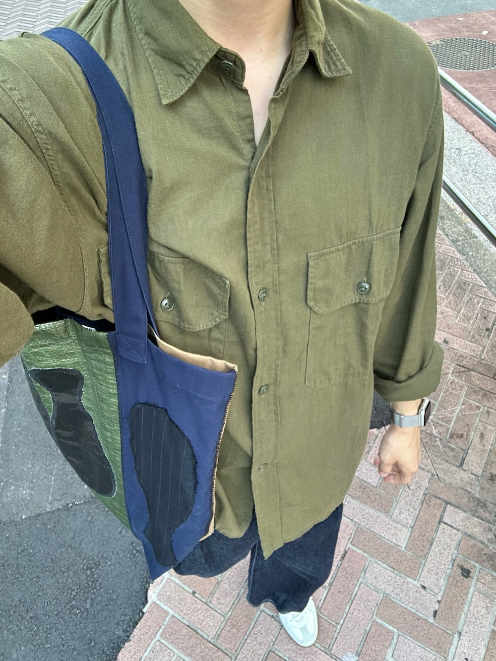 ホワイト系のスニーカー、グリーン系のトートバッグ、グリーン系のシャツ/ブラウスを着用したメンズの秋コーディネートの3枚目の写真