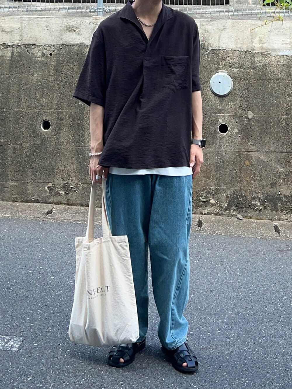 ブルー系のデニムパンツ、ブラック系のサンダル、ベージュ系のトートバッグを着用したメンズの秋コーディネートの2枚目の写真