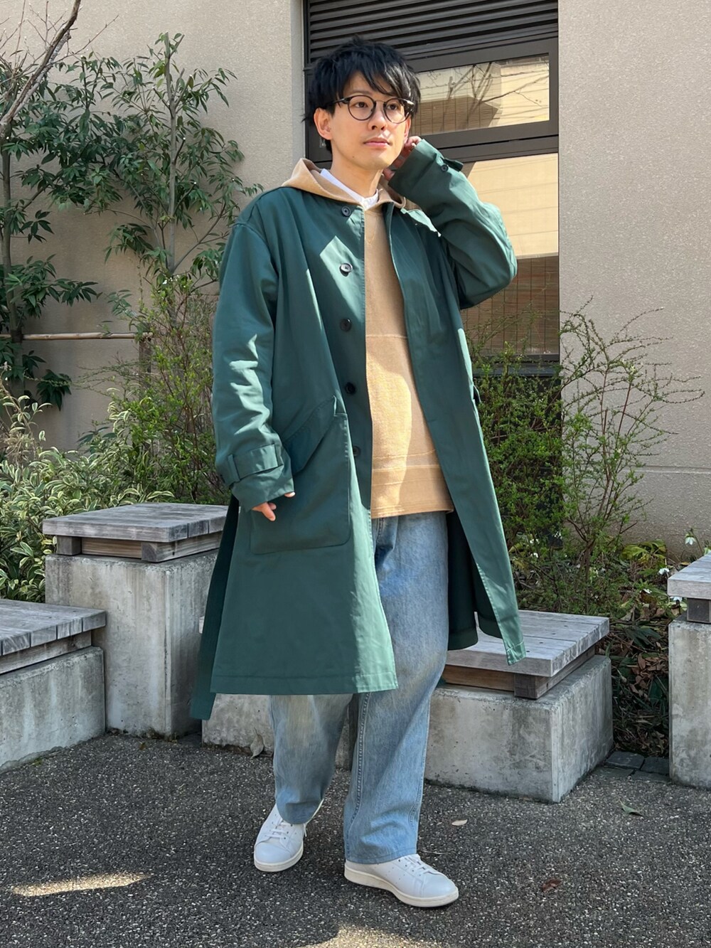 グリーン系のステンカラーコート、ベージュ系のパーカー、ホワイト系のスニーカーを着用したメンズの春コーディネートの2枚目の写真