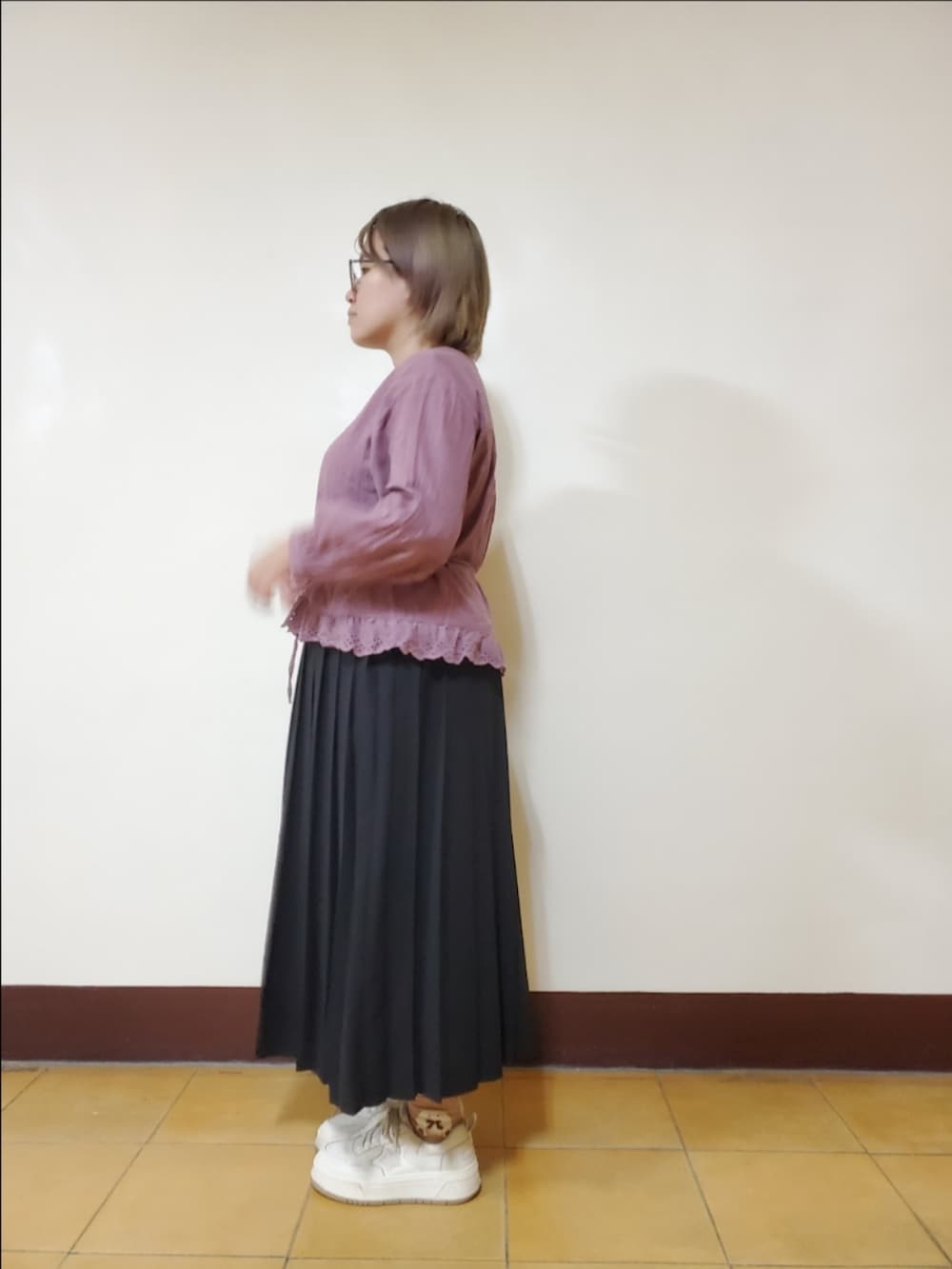 パープル系のワンピース、ブラック系のスカート、ホワイト系のスニーカーを着用したレディースの夏コーディネートの3枚目の写真