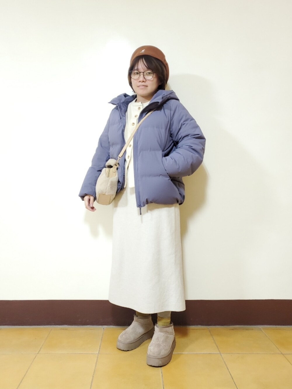 ホワイト系のカーディガン/ボレロ、ベージュ系のスカート、ブラウン系のブーツを着用したレディースの冬コーディネートの2枚目の写真